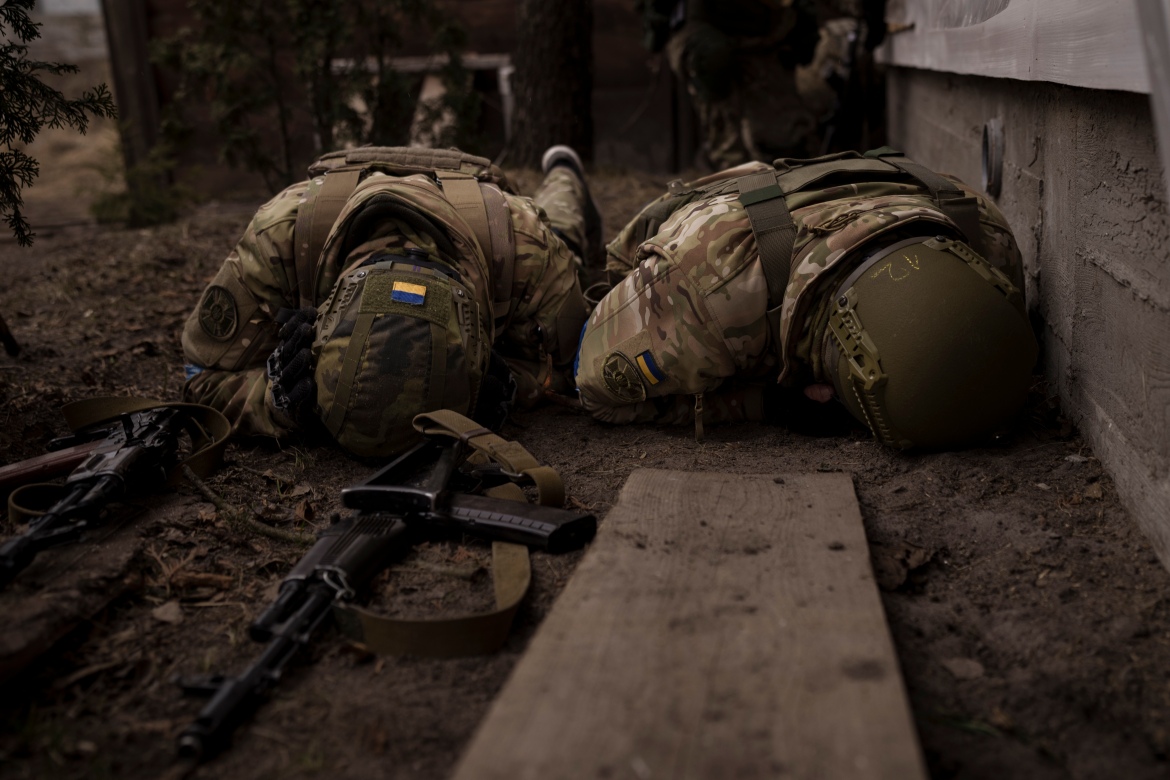 Ukrainian soldiers take cover from incoming artillery fire in Irpin
